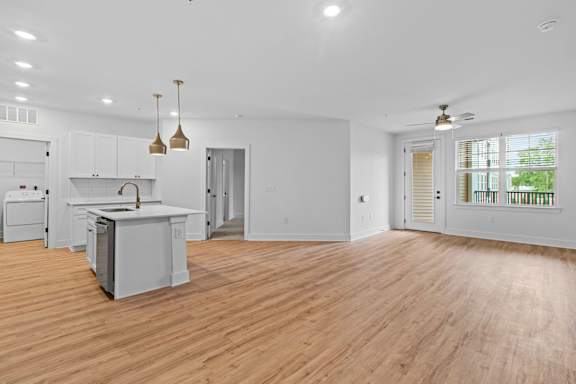 A spacious kitchen with wooden floors and white walls.
