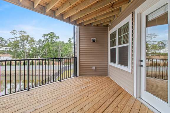 A wooden deck with a sliding glass door leading to a patio.