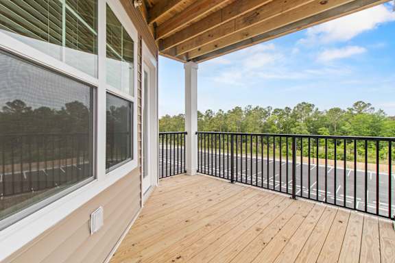 A balcony with a black railing and a wooden floor.