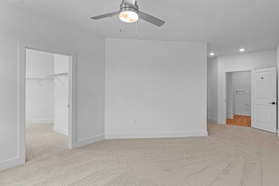 A room with a ceiling fan and carpeted floor.