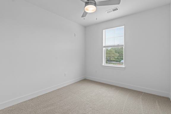 A room with a ceiling fan and a window with blinds.
