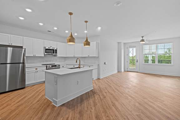 A modern kitchen with a wooden floor and white cabinets.