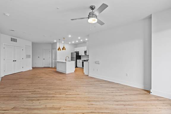 A spacious room with wooden floors and a ceiling fan.