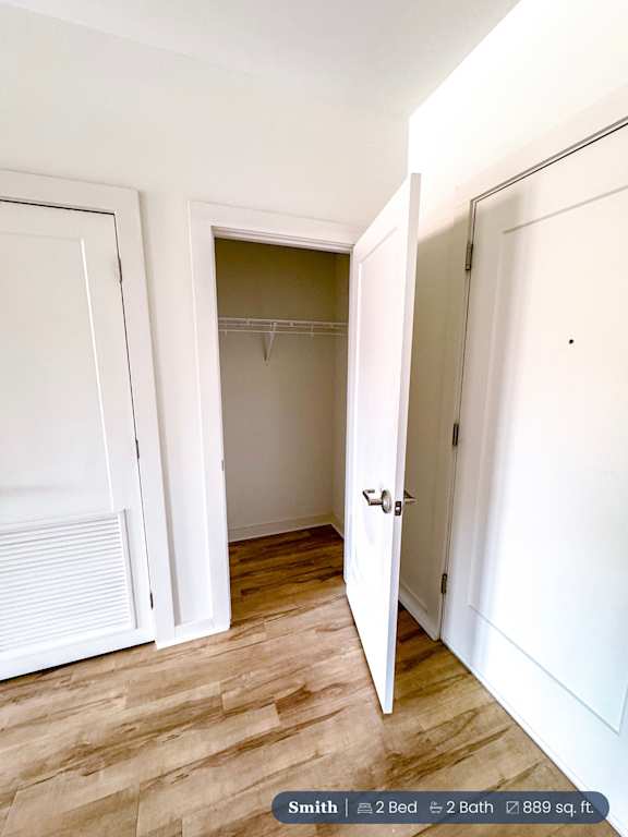 A white door is open to a room with a wooden floor.