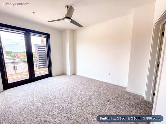 A bedroom with a carpeted floor and a ceiling fan.
