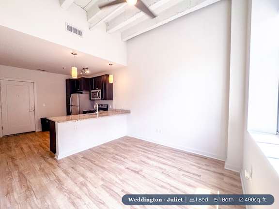 A spacious room with a kitchenette and a window.