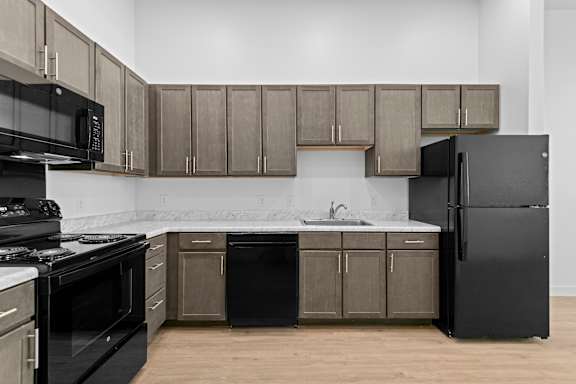 A kitchen with black appliances and brown cabinets.