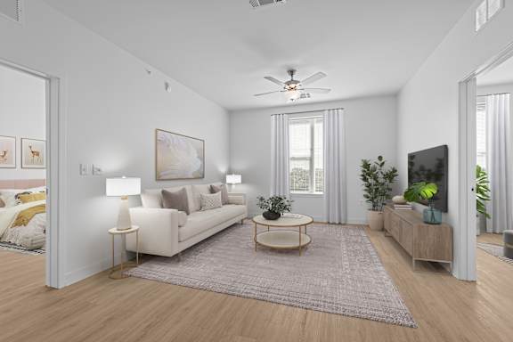 A living room with a white couch, a grey rug, and a ceiling fan.