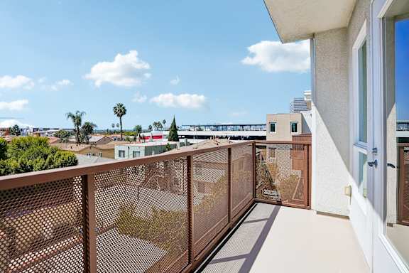 A balcony with a brown railing overlooks a residential area.