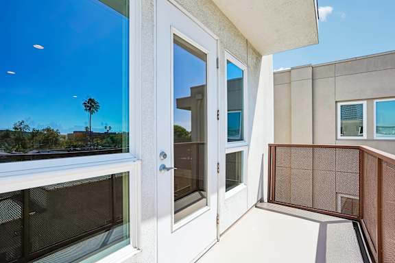 A balcony with a view of palm trees and a clear blue sky.