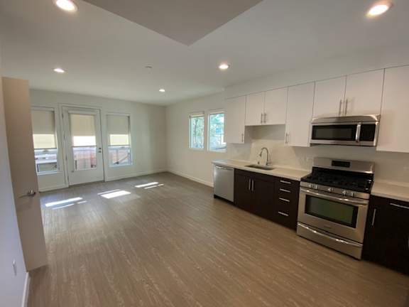 Living room and kitchen area with a sink, dishwasher, gas stove/oven, microwave and cabinets at unit 203, 739 South Ogden Drive.