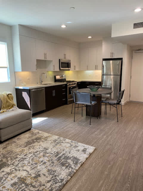 LIving room area and a kitchen with white cabinets, a refrigerator, gas stove, dishwasher and sink at unit 203, 739 South Ogden Drive.