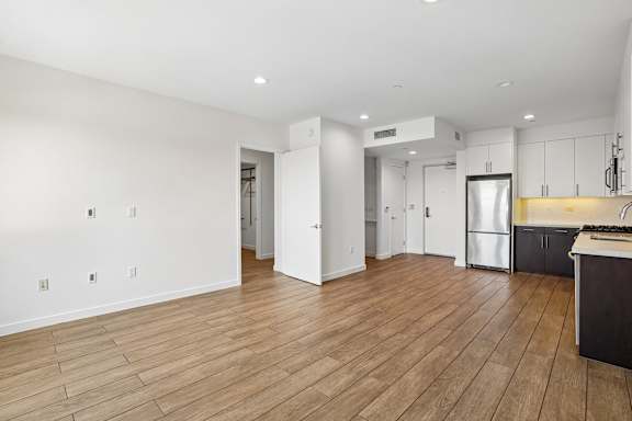 A kitchen area with a refrigerator, cabinets, and a countertop.