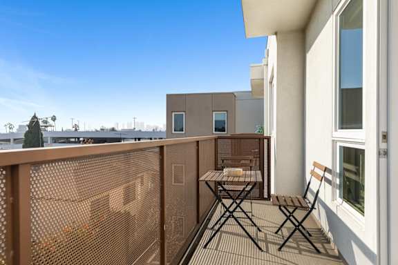 Balcony with a table and chairs overlooks a cityscape.