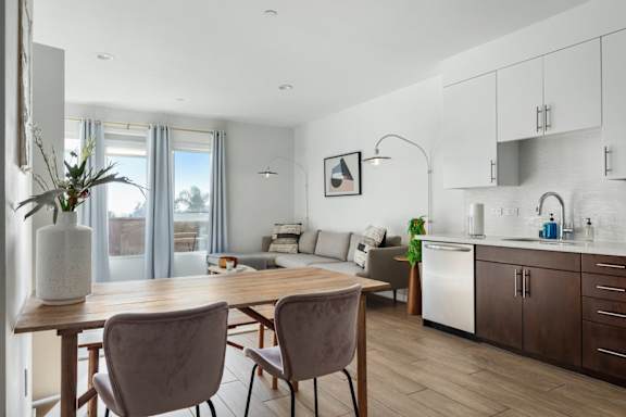 Modern kitchen with a dining table and chairs and a view of the living room.