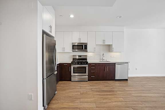 A kitchen with a refrigerator, oven, and microwave.