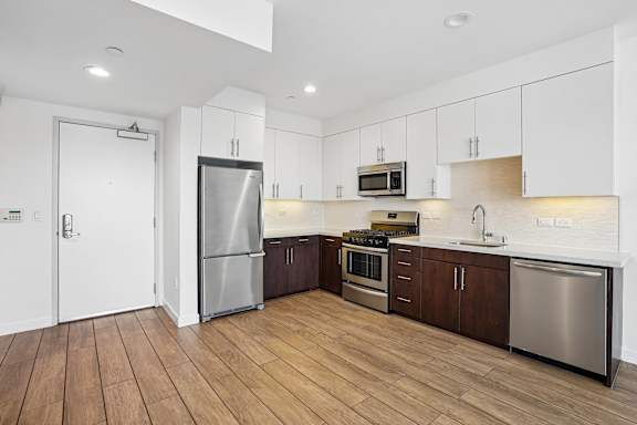 A modern kitchen with wooden floors and stainless steel appliances.