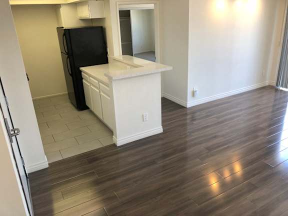 A black refrigerator is in a kitchen with white cabinets and a white countertop.