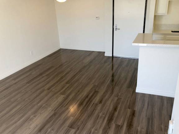 A room with wooden flooring and a white wall.