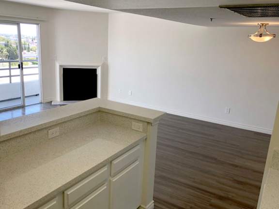 A living room with a fireplace and a kitchen area.