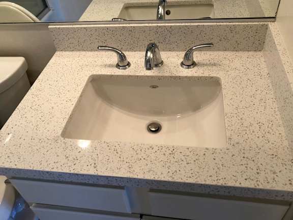 A bathroom sink with a granite countertop and a mirror above it.