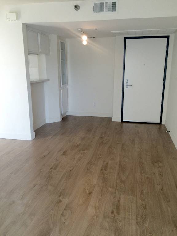 A room with a white door and a wooden floor.