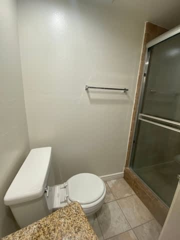 A white toilet in a small bathroom with a glass shower door.