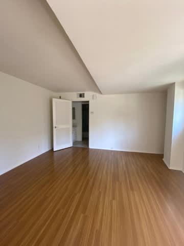 A room with wooden flooring and white walls.