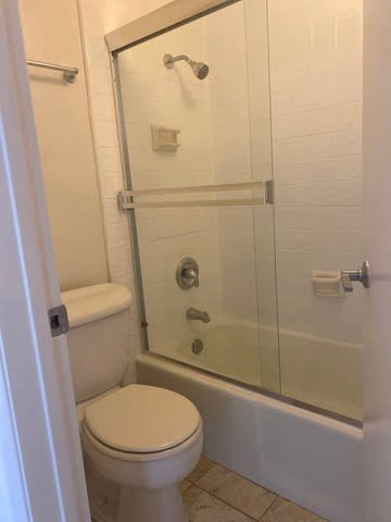A white toilet sits next to a glass shower door in a bathroom.