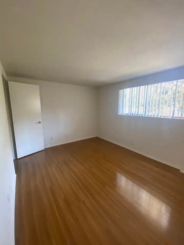 A room with wooden flooring and a window with blinds.