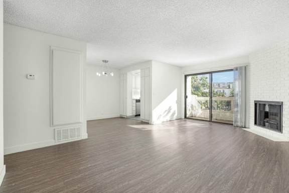 A spacious living room with wooden flooring and white walls.