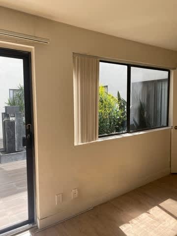 A room with a sliding glass door and a window with curtains.