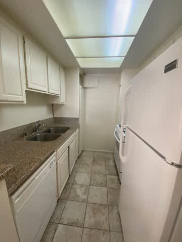 A kitchen with a white fridge and brown countertops.