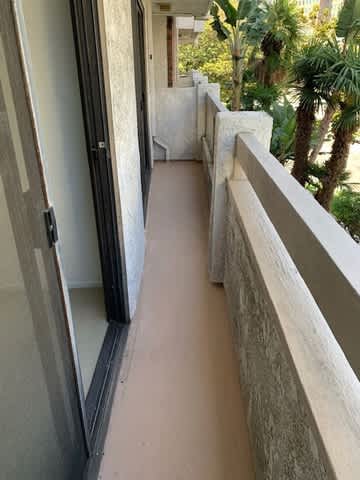 A balcony with a glass door and a concrete wall.