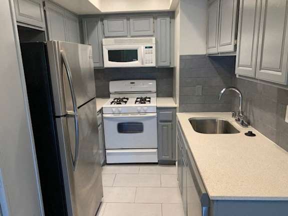 A kitchen with a stove, refrigerator, and microwave.