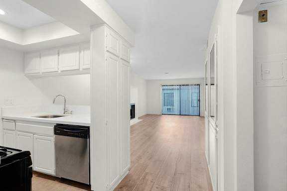 A kitchen with white cabinets and a black dishwasher.