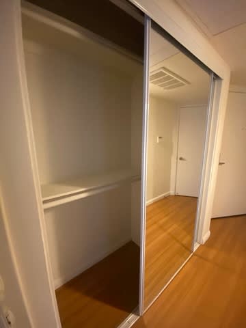 A room with a mirrored door and wooden flooring.