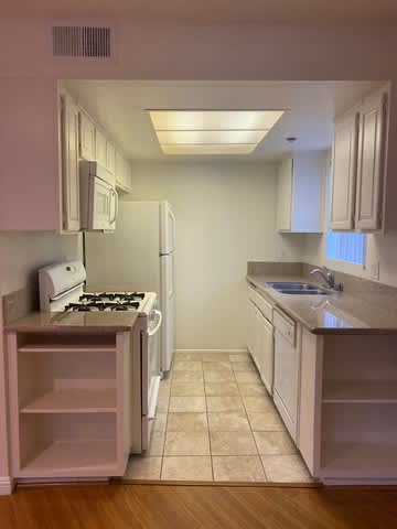 A kitchen with a stove, sink, and refrigerator.