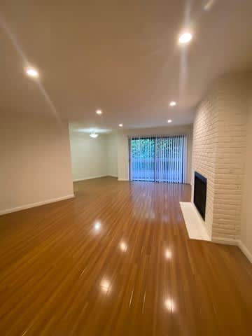 A room with wooden flooring and a fireplace.
