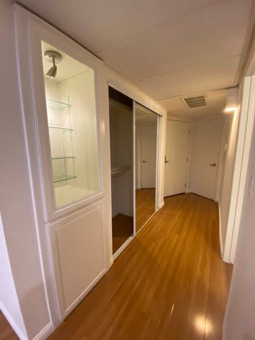 A long hallway with a glass door and wooden floors.