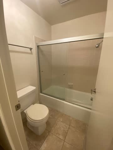 A white toilet sits next to a glass shower door in a bathroom.