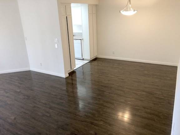 A room with wooden floors and a doorway leading to another room.