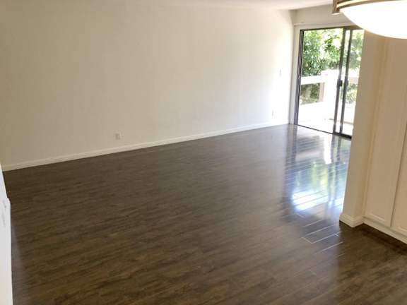 A room with wooden flooring and a sliding glass door.