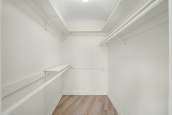 Empty white room with shelves and wood flooring.