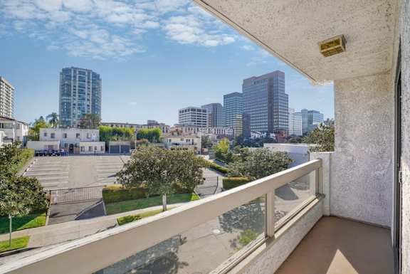 A balcony overlooks a parking lot and a city skyline.