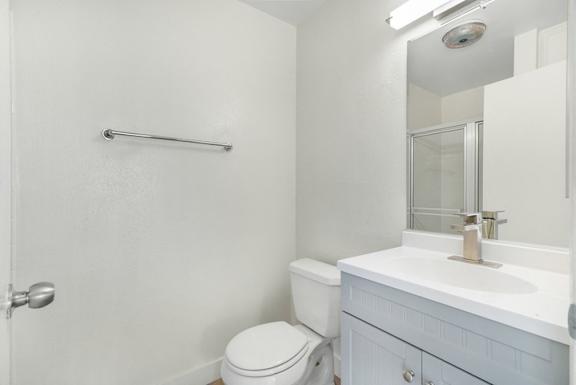 A white bathroom with a toilet, sink, and shower.
