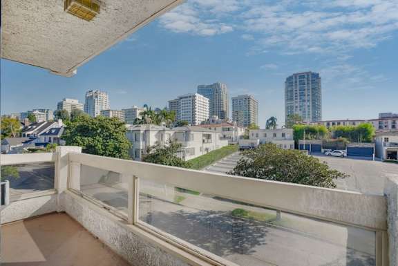 A balcony overlooks a cityscape with buildings and trees.