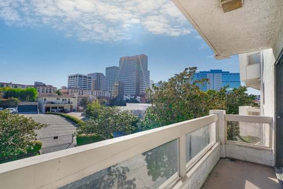 A balcony overlooks a parking lot and buildings.