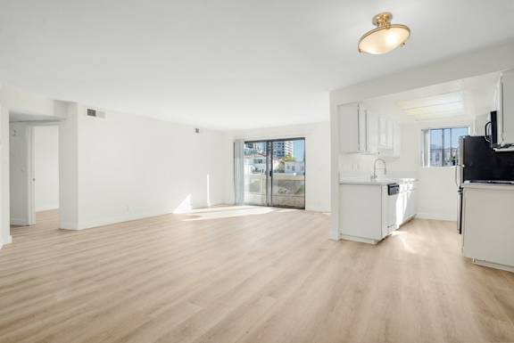 A spacious living room with wooden flooring and white walls.