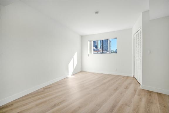 A room with wooden flooring and a window showing a cityscape outside.